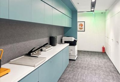 Office printing and supply station with light blue cabinetry and grey carpets.
