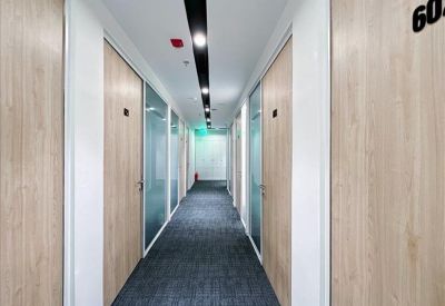 Modern office corridor featuring light wood doors and glass partitions.