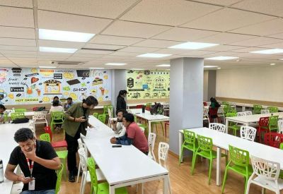 Colorful communal dining area with green chairs and vibrant wall murals.
