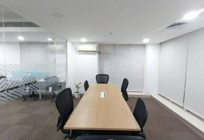 Modern meeting room with a light wood table, black chairs, and large windows with blinds.