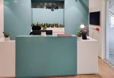 Modern reception desk at Regus Tower with teal accent walls and indoor plants.