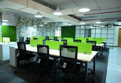 Modern office suite with rows of desks, green partitions, and bright artificial lighting.