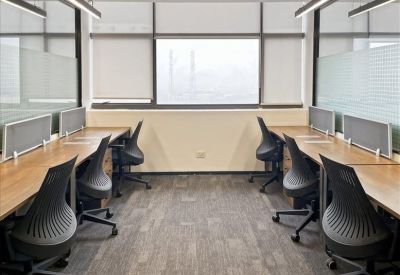 Bright office space with two rows of wooden desks and ergonomic mesh chairs.