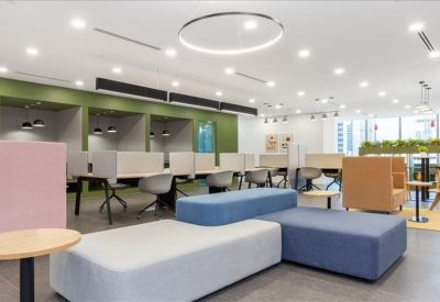 Spacious coworking lounge with varied seating including blue and grey modular sofas.