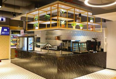 Self-service refreshment bar with a dark marble counter and a decorative overhead plant shelf.