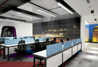 Open-plan office with blue privacy screens and a feature wall showcasing a city skyline at night.