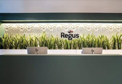 Branded reception desk with a decorative floral wall and indoor plants.