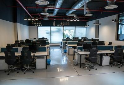 Large open-plan office with rows of modern white desks and black ergonomic chairs.