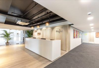 Minimalist white reception desk in a spacious lobby with natural wood flooring.