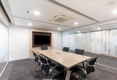 Professional boardroom with a wooden table, black leather chairs, and wall-mounted screen.