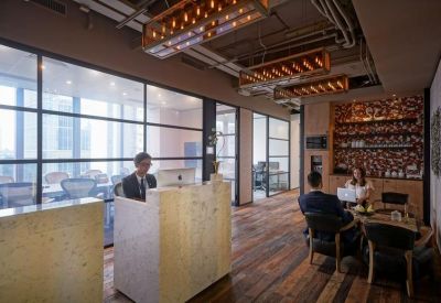 Modern reception desk with warm wooden flooring and unique industrial-style lighting.