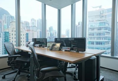 Bright corner office space with wooden desks and ergonomic mesh chairs overlooking the city.