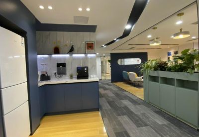 Modern communal kitchen and breakout area with blue cabinetry and wooden flooring.