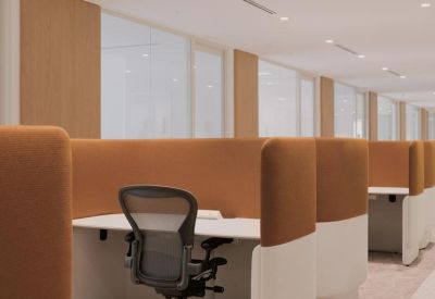 Individual semi-private workstation with tan sound-dampening walls and an ergonomic chair.