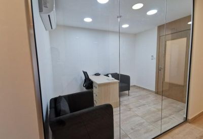Private meeting room with a small desk and armchairs behind a glass partition.