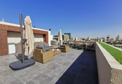Sunny rooftop terrace with outdoor lounge furniture and views of the city skyline.