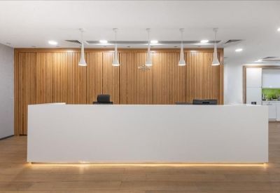 Modern reception area with a minimalist white desk and warm wood-paneled background.