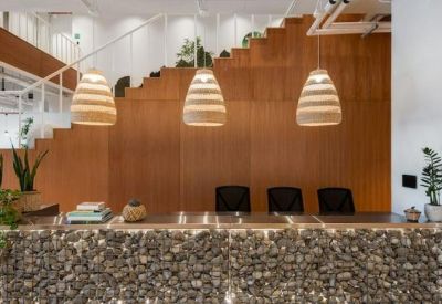 Reception area featuring a gabion stone front desk, wooden feature wall, and pendant lighting.