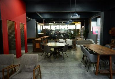 Industrial style coworking space with dark ceilings, red accent walls, and various seating areas.