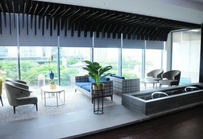 Spacious lounge area with blue sofas and large windows showing greenery.