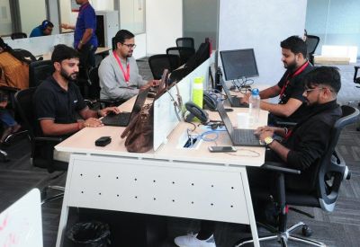 Open-plan office with employees working at white desks with laptops.