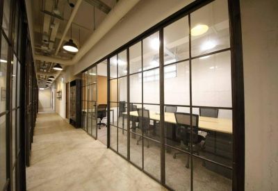 Professional meeting room featuring a long wooden table and glass partitions along a corridor.
