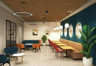 Spacious lounge and dining area with a teal accent wall, warm lighting, and cafe-style seating.