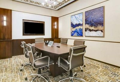 Formal boardroom with a dark wood table, leather chairs, and framed blue abstract art.