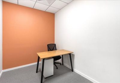 Minimalist single-person office with an orange feature wall and wooden desk.