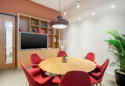 Meeting room at 1st Floor,Riyadh Park, Al Aqiq with a round wooden table, red chairs, and a large wall-mounted screen.