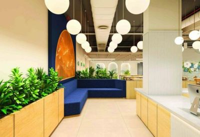 Modern reception area with a blue L-shaped sofa, wooden planters, and spherical pendant lighting.