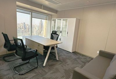 Private office suite with a wooden desk, grey sofa, and city views.