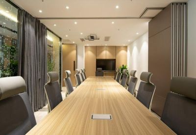 Long wooden boardroom table with modern grey chairs and built-in connectivity.