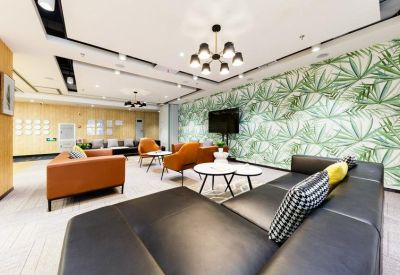 Spacious communal lounge area with leather seating and a tropical leaf feature wall.