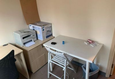 Compact private office with a white desk, folding chair, and printer setup.