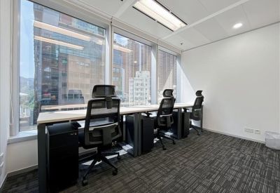 Bright office space with desks facing a large window overlooking the city.