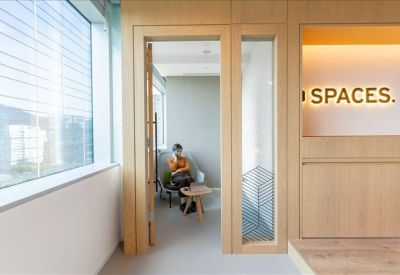 Small private booth with a wooden door and glass panel, featuring a person working inside.