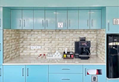 Modern office pantry with light blue cabinetry and a patterned brick-style backsplash.
