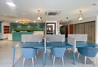 Open-plan coworking space with teal desks and grey privacy dividers.