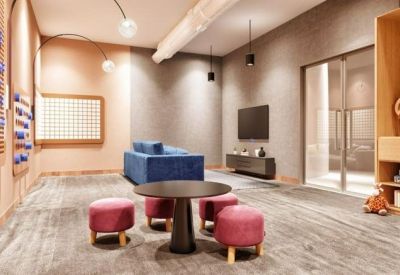 Vibrant children's play area with a blue sofa, pink stools, and wall-mounted games.