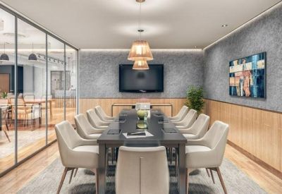 Professional meeting room with a long dark table, cream-colored chairs, and a wall-mounted TV.