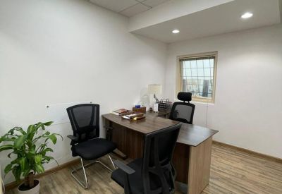 A two-person office suite with dark wood desks and natural light from a small window.