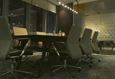 Sleek board room with high-back grey chairs and a dark wood table under a modern light fixture.
