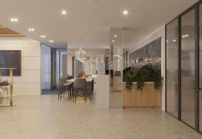 Spacious breakout lounge with a large wooden communal table and greenery.