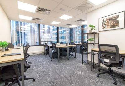 Bright shared office space with multiple wooden desks and large windows.