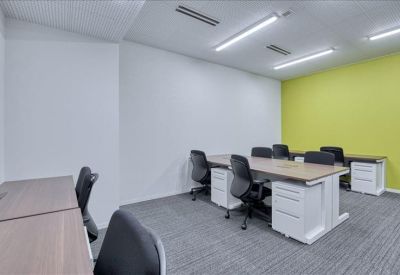 Open-plan workspace with multiple desks and a bright lime green accent wall.