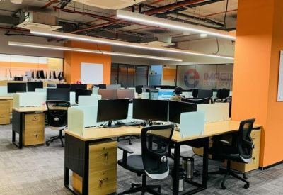 Spacious open-plan office with orange feature columns and rows of wooden workstations.