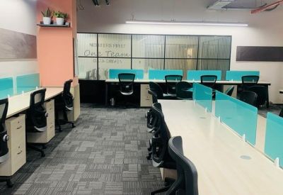 Bright workspace featuring teal privacy screens, light wood desks, and grey patterned carpeting.