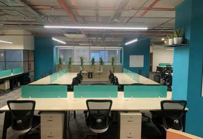 Modern office interior with teal walls, white desks, and exposed ceiling pipes with industrial lighting.