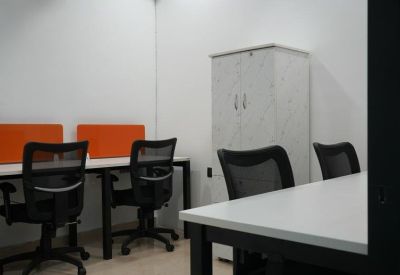 Internal private office suite with white desks, orange privacy screens, and black ergonomic chairs.